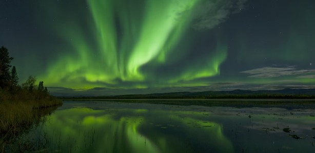 Northern lights lighting up the evening sky above a lake