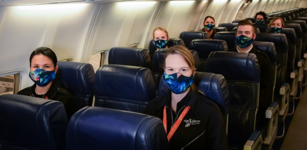 Air North staff wearing cloth safety masks while sitting in seats on a plane