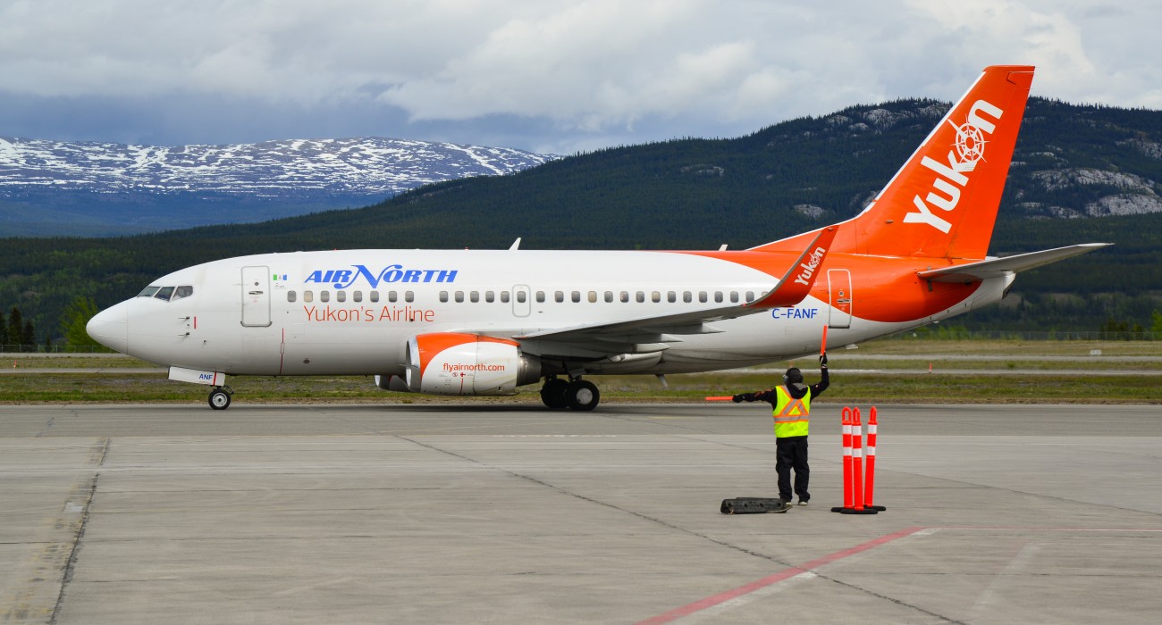 An Air North plane on the runway with mountains in the background