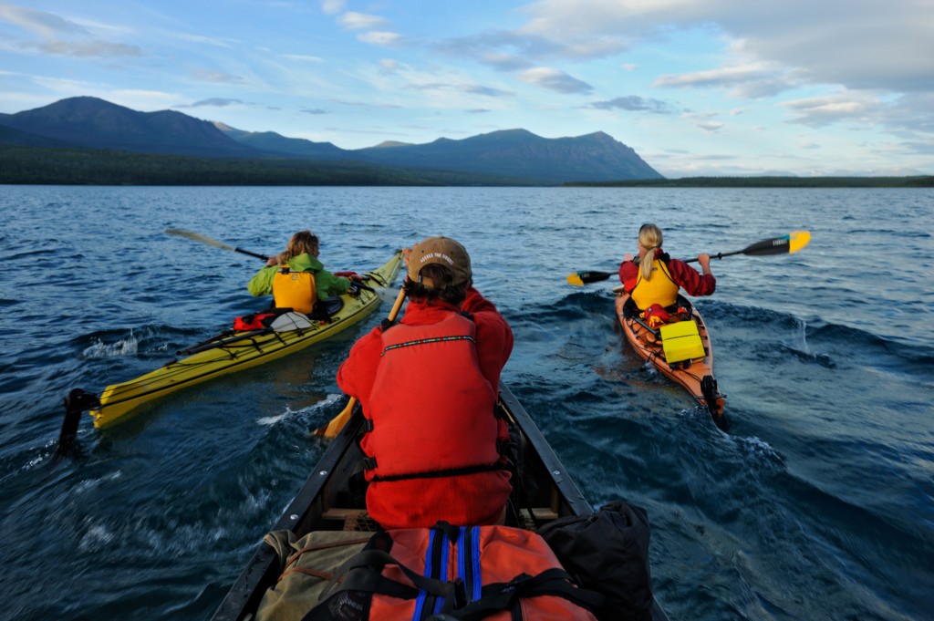 Three people paddling with life jackets. 