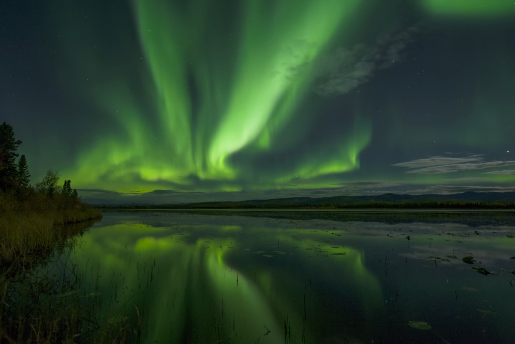 Northern lights lighting up the evening sky above a lake
